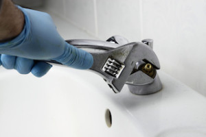 Tap fixing spanner / Man fixing tap in a bathroom with a spanner.