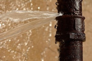 Rusty burst pipe squirting water at high pressure