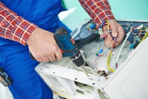 Washing machine repair. Repairer hands with screwdriver disassembling damaged unit for repair